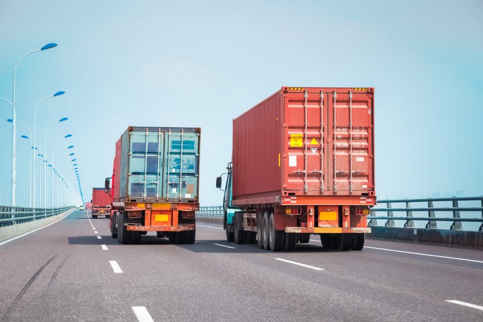 Två lastbilar med containrar på vägen